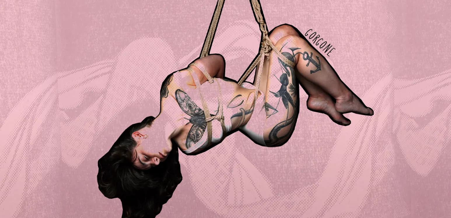 Tattooed woman suspended with a torsion in shibari ropes against pink textured background.