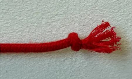 A red rope with a frayed knot end on a white background.