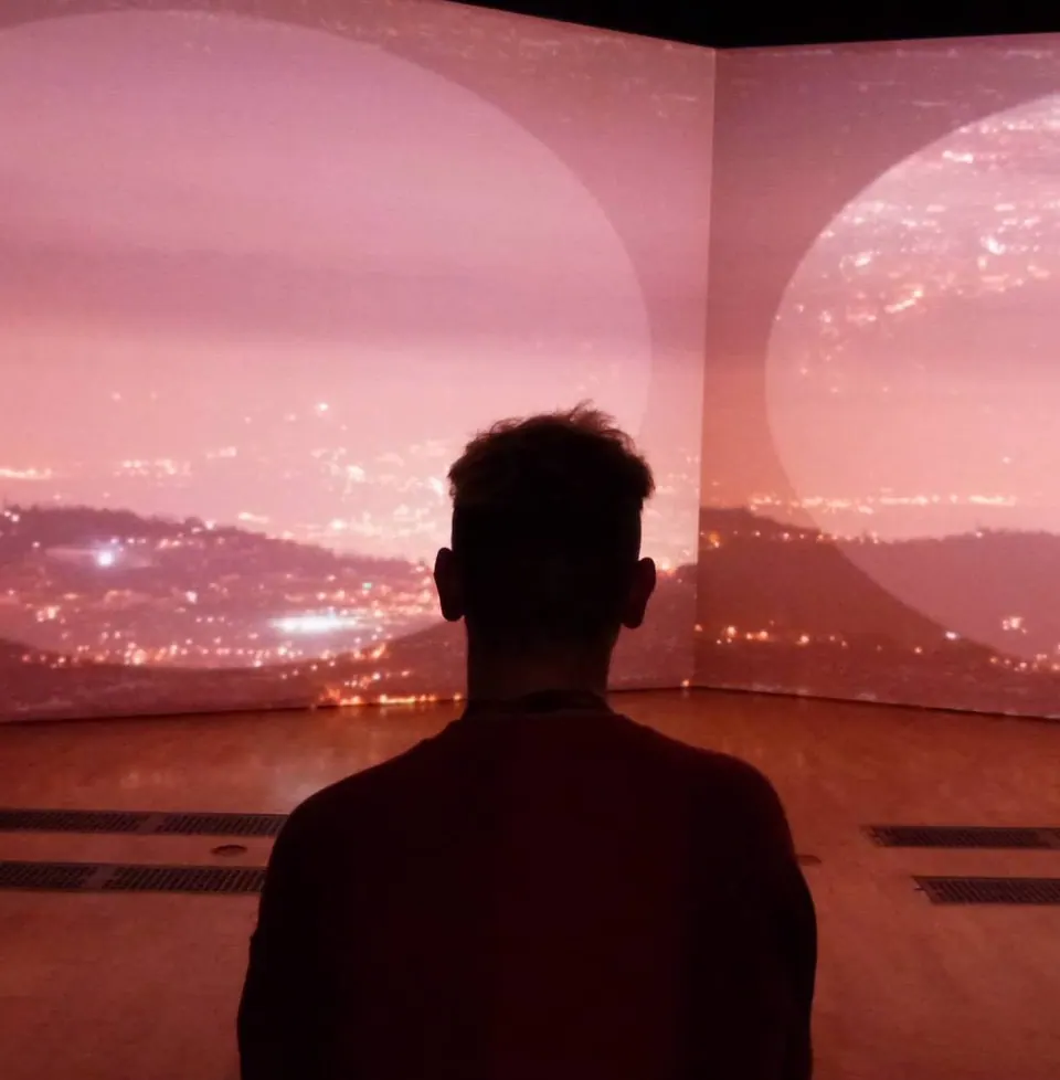 A person silhouetted against a wall-sized projection of a city at night.