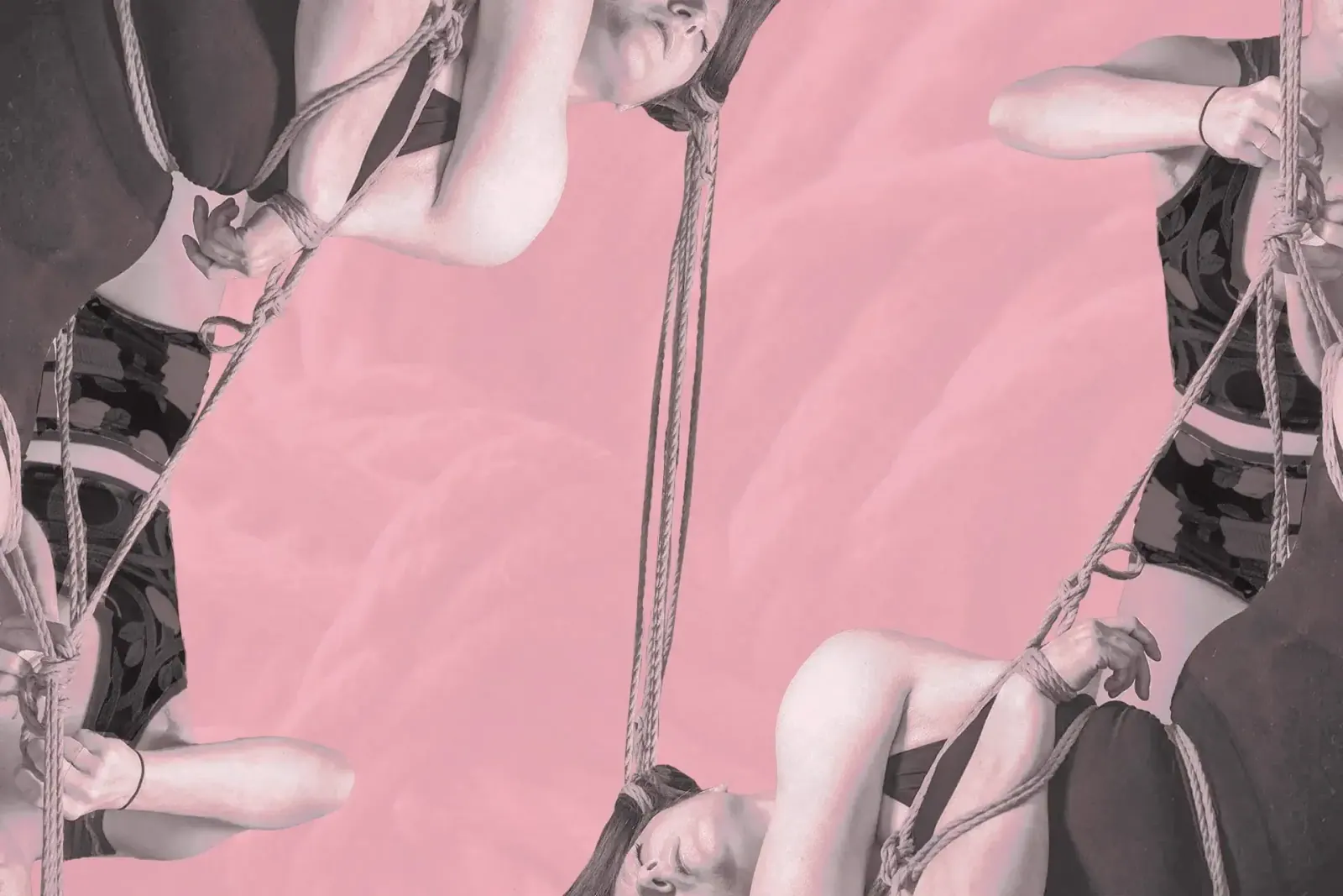 A rigger and bottom are tying a shibari suspension with hair rope on a pink background.