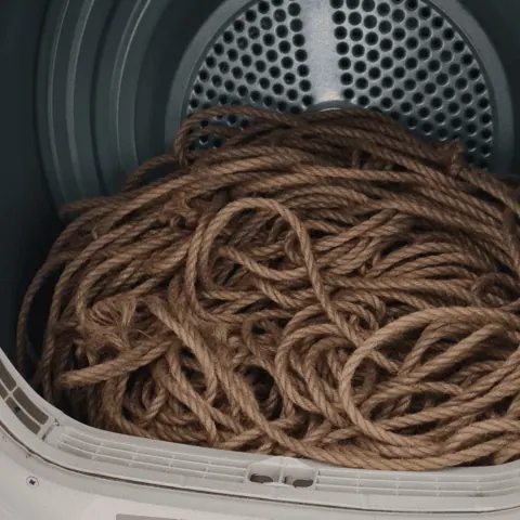 Bundled jute rope spinning inside a washing machine drum during cleaning.