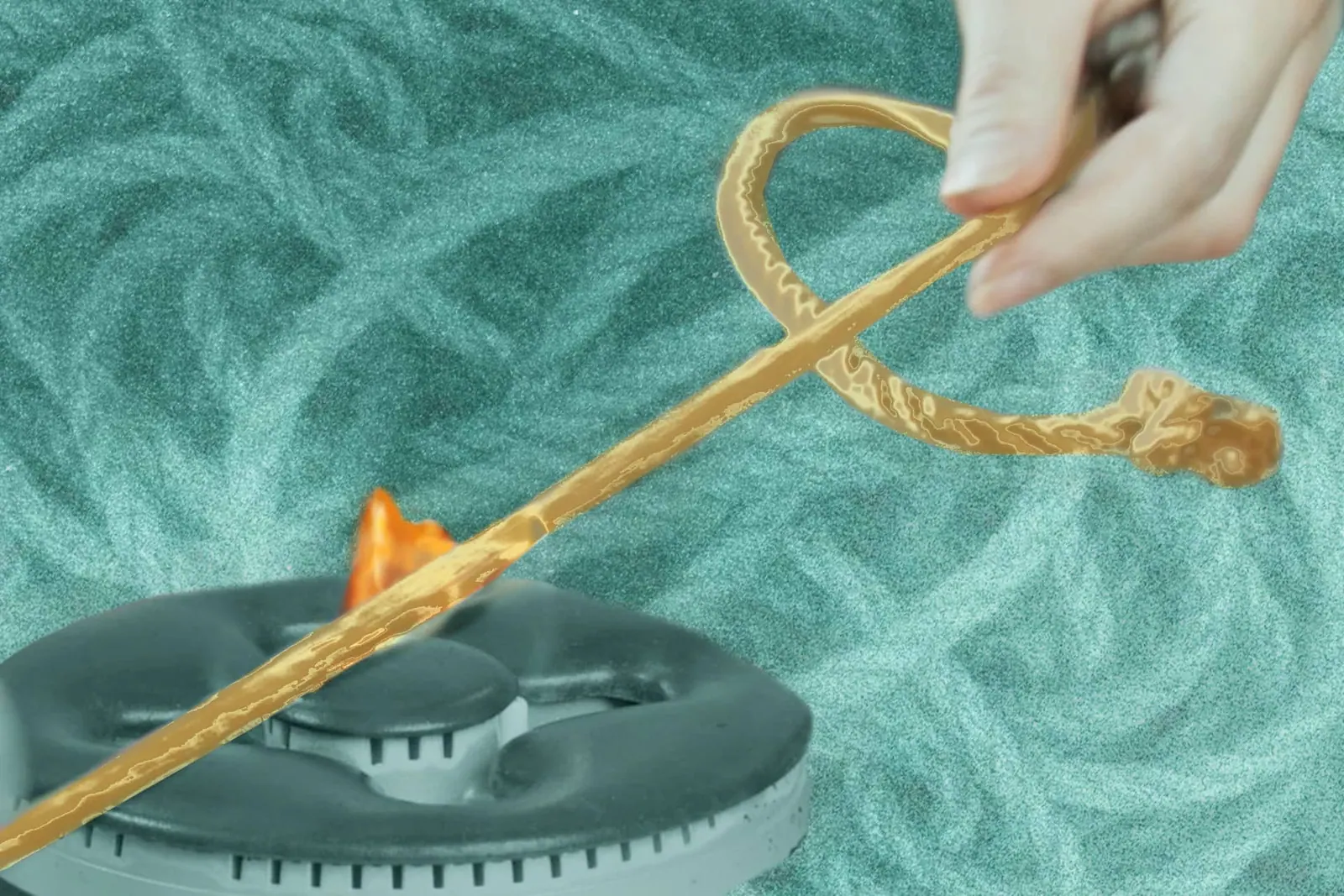 Hand holding jute rope burning off fuzzies over a gas burner with a teal rope background.