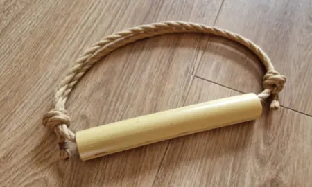 Worn jute rope coiled around a bamboo rod on wooden flooring.